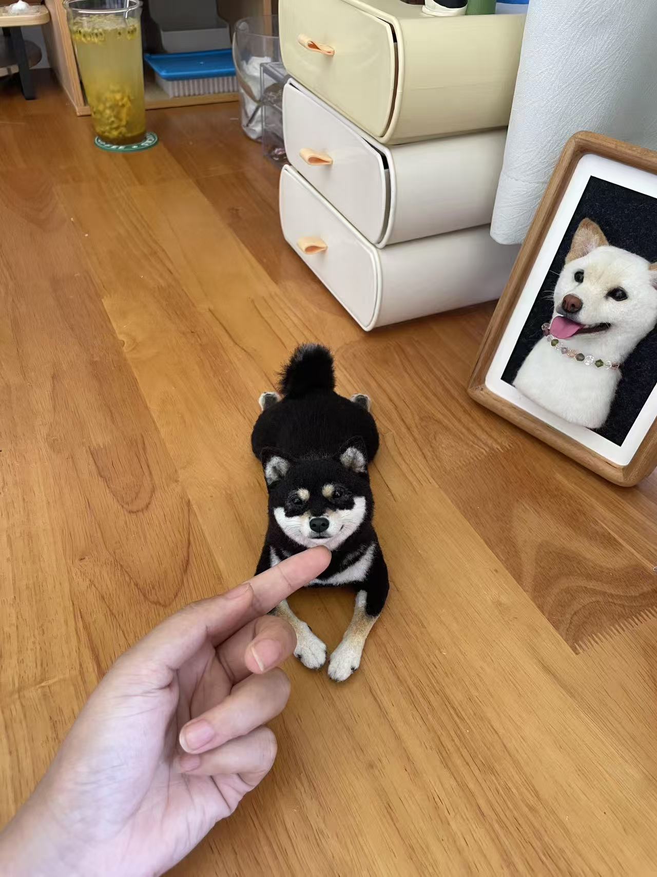 Small black dog wool felt sculpture displayed beside a framed portrait